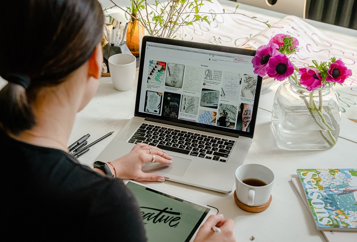 femme-avec-ordinateur-portable-avec-images-sur-fond-blanc-tasse-de-cafe-vase-transparent-avec fleurs-roses