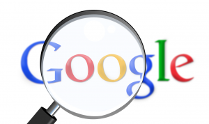 lettres du mot google en bleu rouge jaune bleu vert rouge représentées derrière une loupe